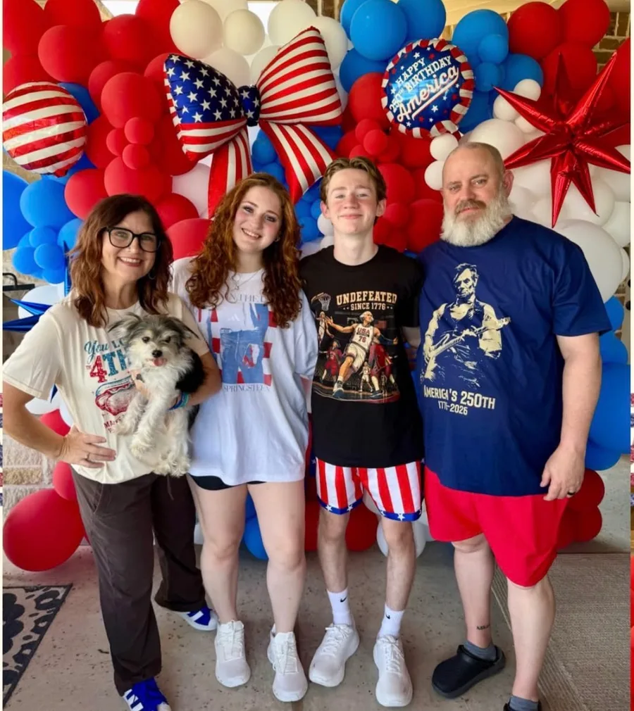 Becky with her family and their dog in front of a patriotic balloon installation she designed